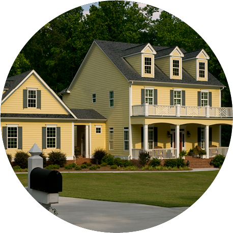 A yellow, two-story house with a front porch and green grass.